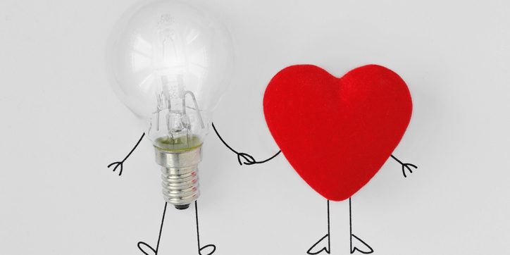 Light bulb and heart holding hands – Concept of brain and heart teamwork
